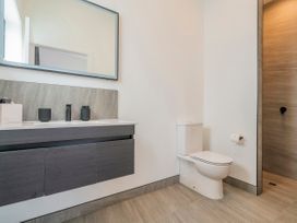 A bathroom with a sink, mirror, and toilet at Sun and Sea Sanctuary - Whitianga