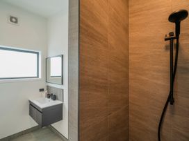 A bathroom with a sink and mirror near a shower at Sun and Sea Sanctuary - Whitianga