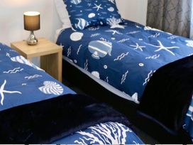 Two beds with blue bedding and a lamp on a side table at Sun and Sea Sanctuary - Whitianga