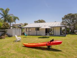 A kayak in the yard with a house and outdoor furniture at Whitianga Holiday Home in Whitianga