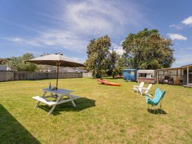 A garden with a picnic table and umbrella at Whitianga Holiday Home Whitianga