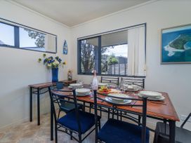 A dining room with a table set and flowers at Whitianga Holiday Home in Whitianga