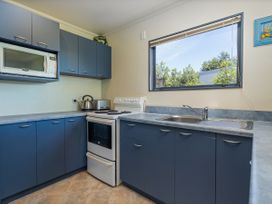 A kitchen with a stove and sink at Whitianga Holiday Home in Whitianga