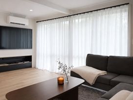 A living room with a television, sofa, and coffee table at Peaks and Pines Chalet - Ohakune