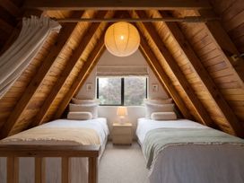 A bedroom with two beds and a lamp at Peaks and Pines Chalet - Ohakune