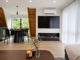 A living room with a television and dining area at Peaks and Pines Chalet - Ohakune