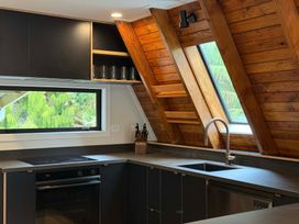 A kitchen with a sink, oven, and shelves at Peaks and Pines Chalet - Ohakune