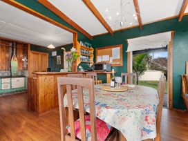 A kitchen with a dining table and chairs at Beachy Bach - Mangawhai Heads