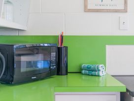 A kitchen with a microwave and towels at Ocean Whispers - Whitianga Holiday Home