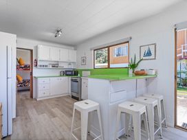 A kitchen with white cabinets and a green countertop at Ocean Whispers - Whitianga