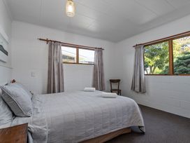 A bedroom with a bed and windows at Ocean Whispers - Whitianga Holiday Home Whitianga