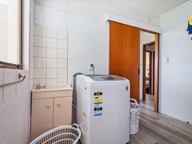 A laundry room featuring a washing machine and sink at Ocean Whispers - Whitianga