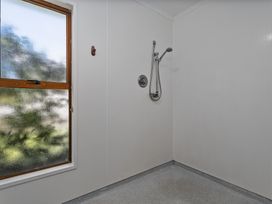 A shower area with a showerhead and a window at Ocean Whispers - Whitianga
