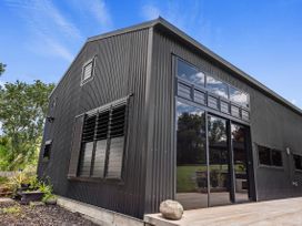 A modern building with large windows and a garden area at Black Dune in Waipu