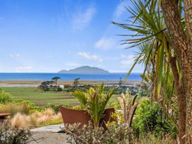 A garden view with plants and ocean at Black Dune in Waipu