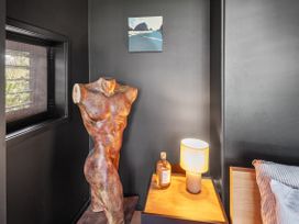 A bedroom with a sculpture and a lamp at Black Dune in Waipu