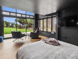 A bedroom with a bed and armchair at Black Dune in Waipu