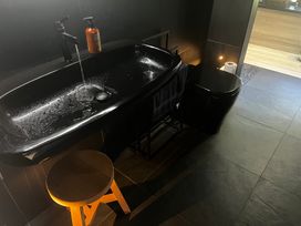 A bathroom with a sink, toilet, and stool at Black Dune in Waipu
