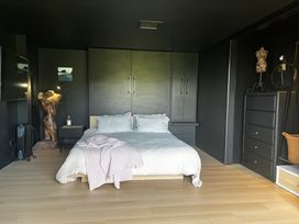 A bedroom with a bed and wardrobe at Black Dune in Waipu