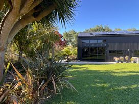 A garden with a building and plants at Black Dune in Waipu