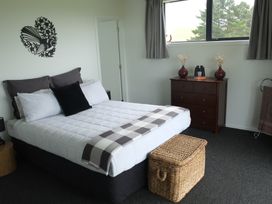 A bedroom with a bed and dresser at Moeraki Holiday Home in Moeraki