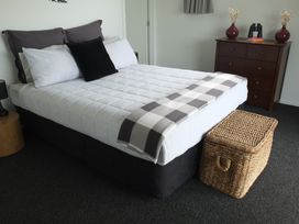 A bedroom with a bed and dresser at Moeraki Holiday Home in Moeraki