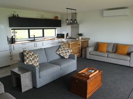 A living room with a sofa and kitchen area at Moeraki Holiday Home Moeraki