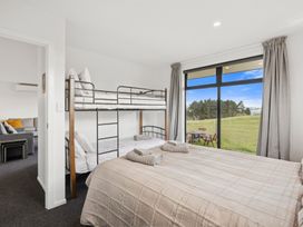 A bedroom with a bunk bed and a double bed at Seabreeze Lookout - Moeraki