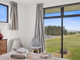 A bedroom with a bed and window view at Seabreeze Lookout - Moeraki