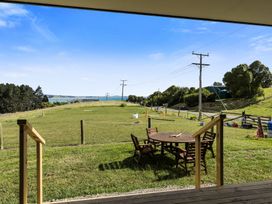 An outdoor area with a table and chairs overlooking a grassy field at Seabreeze Lookout - Moeraki Holiday Home Moeraki