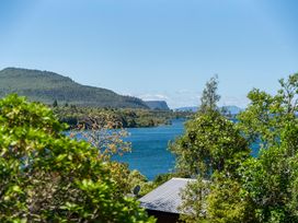 A view of mountains and a lake with trees at Lake Taupo Holiday Home in Turangi