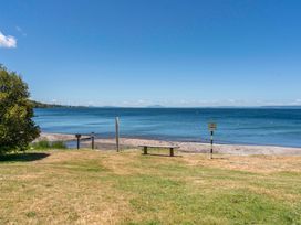 A lake with a bench and a sign at Lake Taupo Holiday Home in Turangi