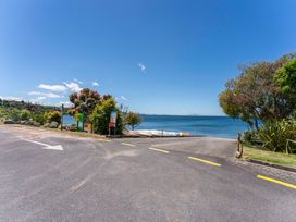 A view of a lakeside road with trees and water at Lake Taupo Holiday Home in Turangi