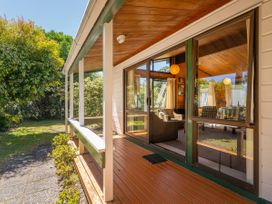 A porch with a view of furniture through large windows at Pauanui Sea Esta, Pauanui