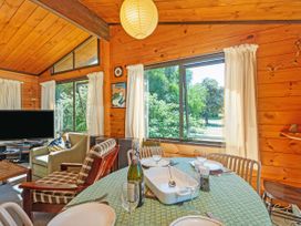 A dining room with a table set and a television at Pauanui Sea Esta in Pauanui