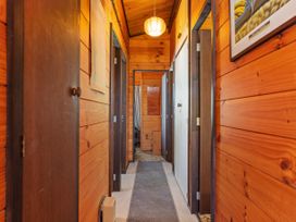 A hallway with wooden walls and multiple doors at Pauanui Sea Esta, Pauanui