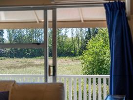 View from a living room window looking at grass and trees at Lake Taupo Holiday Home in Turangi