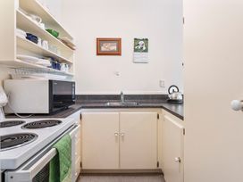 A kitchen with a stove, microwave, and sink at Lake Taupo Holiday Home in Turangi
