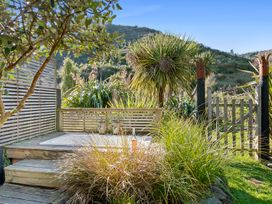 A hot tub on a wooden deck surrounded by plants at Brook Beauty - Nelson Holiday Home, Nelson