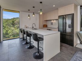 A kitchen with a refrigerator, sink, and bar stools at Tutukaka, Whangarei