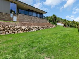 A house with a deck and stone wall in the yard at Tutukaka in Whangarei