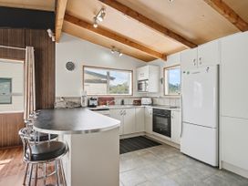 A kitchen with appliances and bar stools at Whitianga