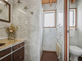 A bathroom with a vanity, sink, shower, and toilet at Whitianga