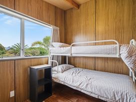 A bedroom with a bunk bed and a shelf at Whitianga