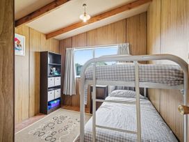 A bedroom with a bunk bed and a bookcase at Whitianga