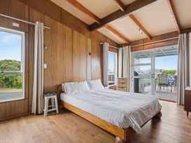 A bedroom with a bed, window, and a chair at Whitianga
