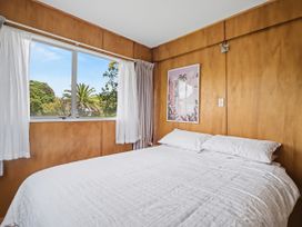 A bedroom with a bed and curtains at Whitianga