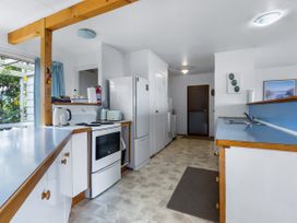 A kitchen with cabinets and appliances at Tides and Time Bach - Ahipara Holiday Home Kaitaia