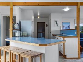 A kitchen with a refrigerator and counter at Tides and Time Bach - Ahipara Holiday Home Kaitaia