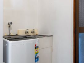 A laundry room with a washing machine and a sink at Tides and Time Bach - Ahipara Holiday Home Kaitaia